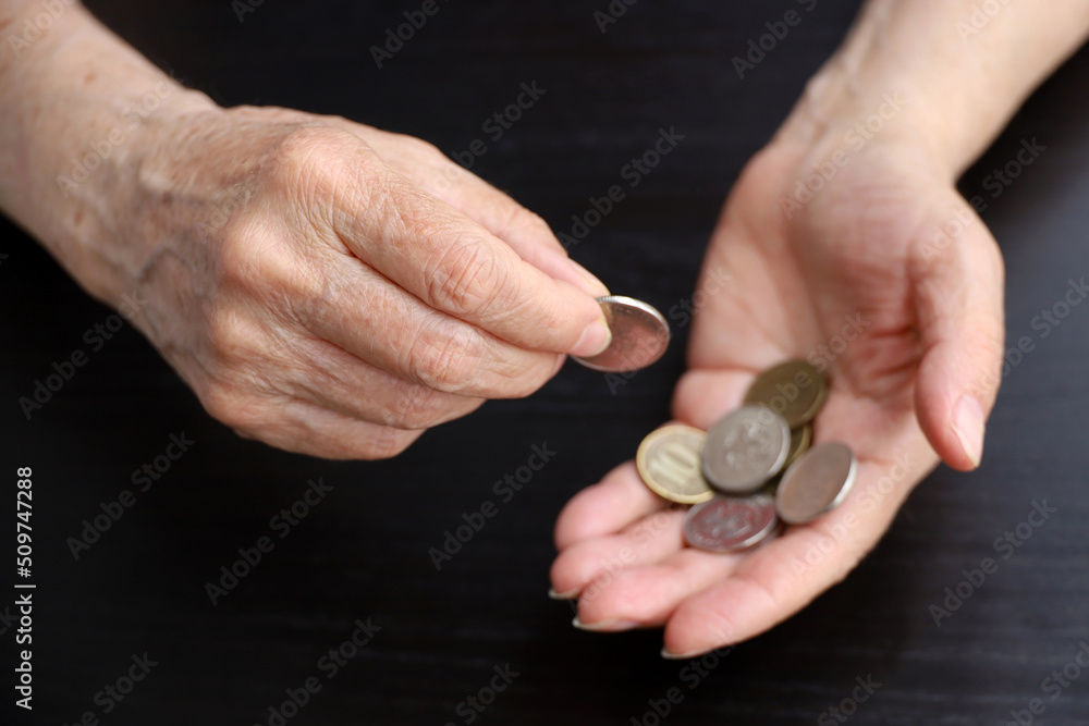 Elderly woman counts metal coins, wrinkled female hands close up. Concept of poverty, pension payments, retiree with money