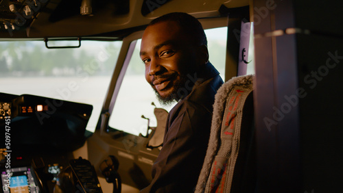 Photographie Portrait of african american copilot sitting in airplane cockpit with captain, ready to fly airline plane with control panel dashboard
