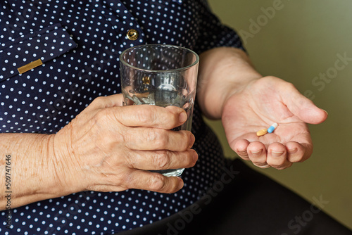 Elderly woman with a glass of water is going to take pills