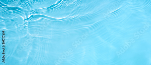 Fototapeta Naklejka Na Ścianę i Meble -  Transparent blue clear water wave surface texture with splashes and bubbles. Abstract summer banner background Water waves in sunlight with copy space Cosmetic moisturizer micellar toner emulsion