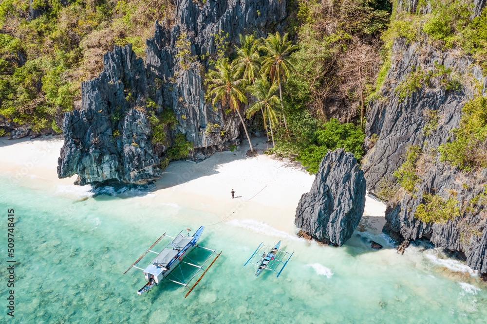 View from above, stunning aerial view of a person on the Entalula Beach, a white sand beach bathed by a crystal clear water. Entalula island, Bacuit Bay, El Nido, Palawan, Philippines.