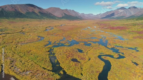 Slow backward drone flight over tundra landscape with mountains, meandering rivers and swamps in autumn colors in the vicinity of Nome, Alaska photo
