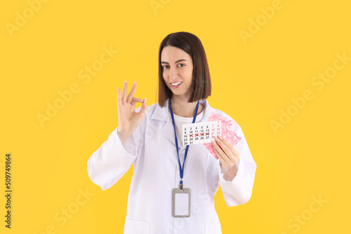 Attractive young female doctor on yellow background