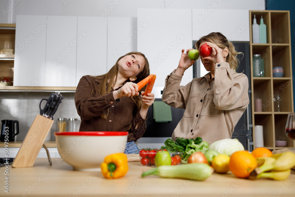 Mother and her adult daughter preparing healthy food and having fun in the kitchen Mother and her adult daughter preparing healthy food and having fun in the kitchen