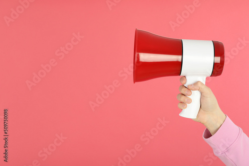 Female hand holds megaphone on pink background