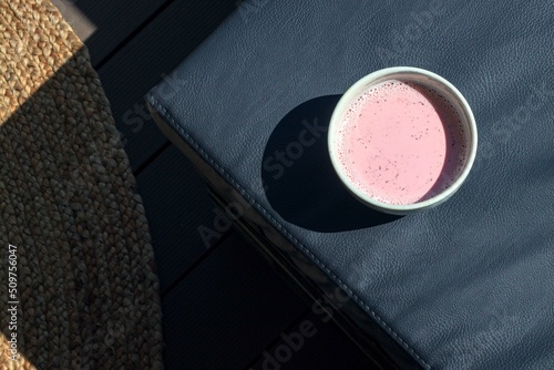pink matcha latte in a large cup on the leather sofa of the cafe's outdoor terrace hard sunlight. High quality photo