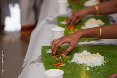 Traditional South Indian food served on plantain leaf in a row. Rice, sambar, salads, etc. Eating with hands.