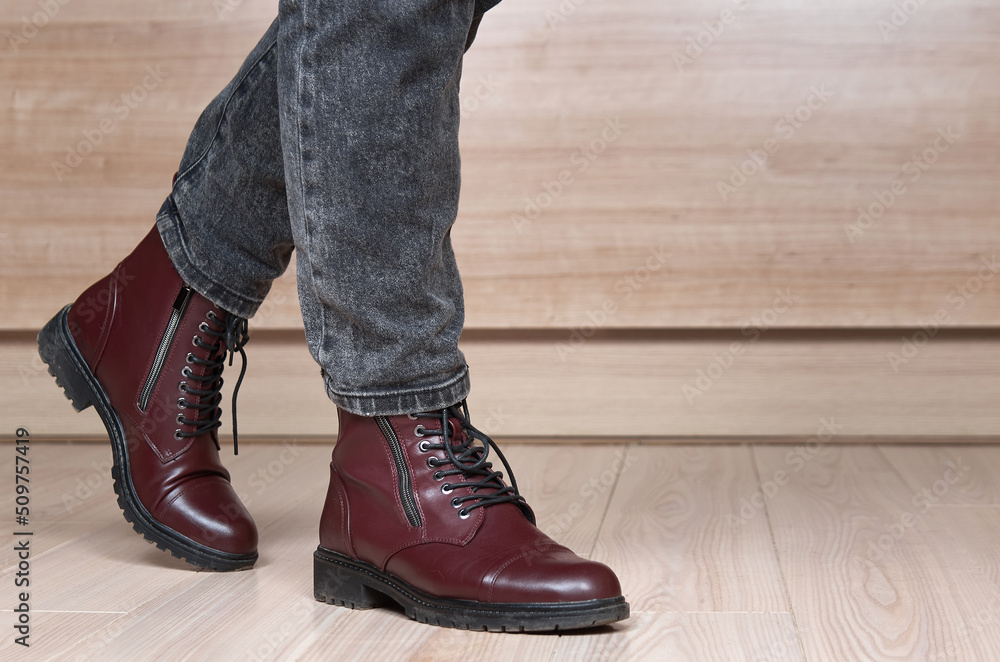 Closeup of stepping woman legs in red leather boots and black jeans