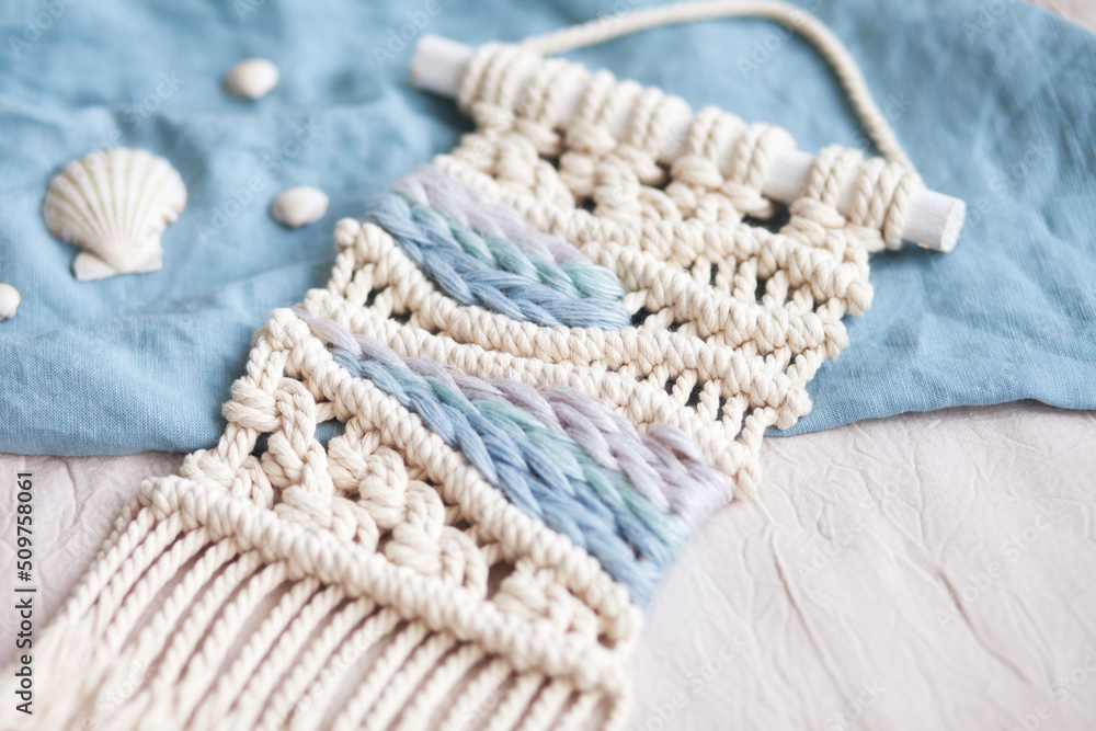 Handmade macrame. 100% cotton wall hanging decoration. Maritime theme. Macrame braiding and cotton threads. Female hobby. ECO friendly modern knitting DIY natural decoration concept in the interior Handmade macrame. 100% cotton wall hanging decoration. Maritime theme. Macrame braiding and cotton threads. Female hobby. ECO friendly modern knitting DIY natural decoration concept in the interior