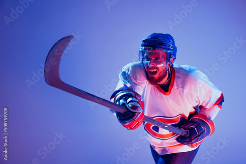 In action. Professional hockey player in sports uniform and protective equipment skating isolated on purple background. Concept of sport, active lifestyle, motion, movement, ad.