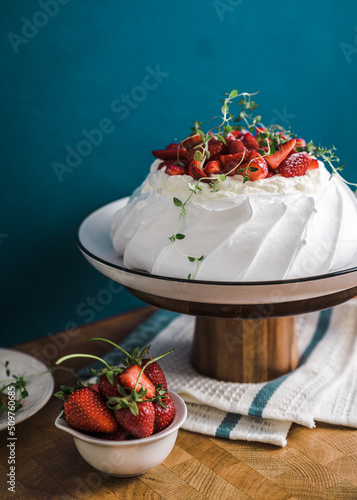 summer dessert of Pavlova with strawberries and whipped cream on blue background