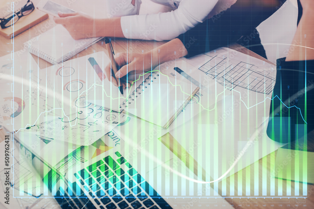 A woman hands writing information about stock market in notepad. Forex chart holograms in front. Concept of research. Double exposure A woman hands writing information about stock market in notepad. Forex chart holograms in front. Concept of research. Double exposure