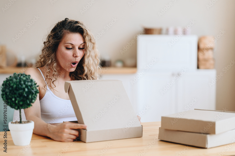 girl opens her mouth in surprise, looking into box. girl holds Parcel in her hands. Home delivery. girl opens her mouth in surprise, looking into box. girl holds Parcel in her hands. Home delivery.