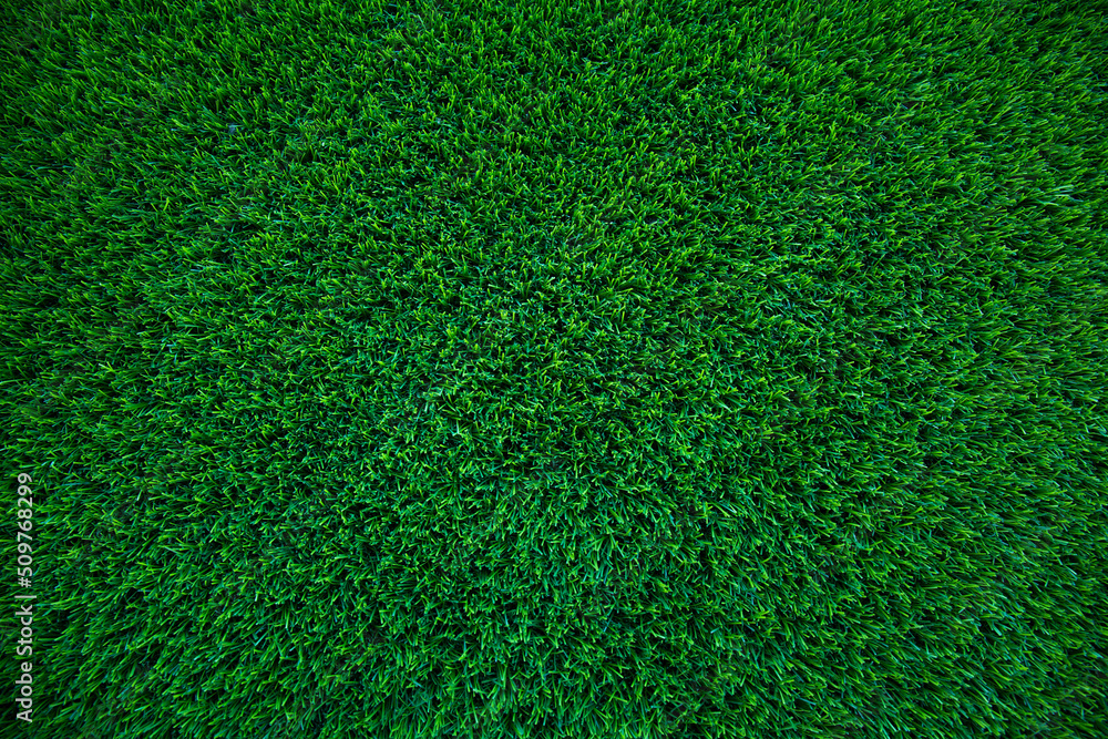 Fototapeta premium Top view of artificial green grass texture for background. Abstract concept design picture backdrop for golf course and sports soccer field or add text message.