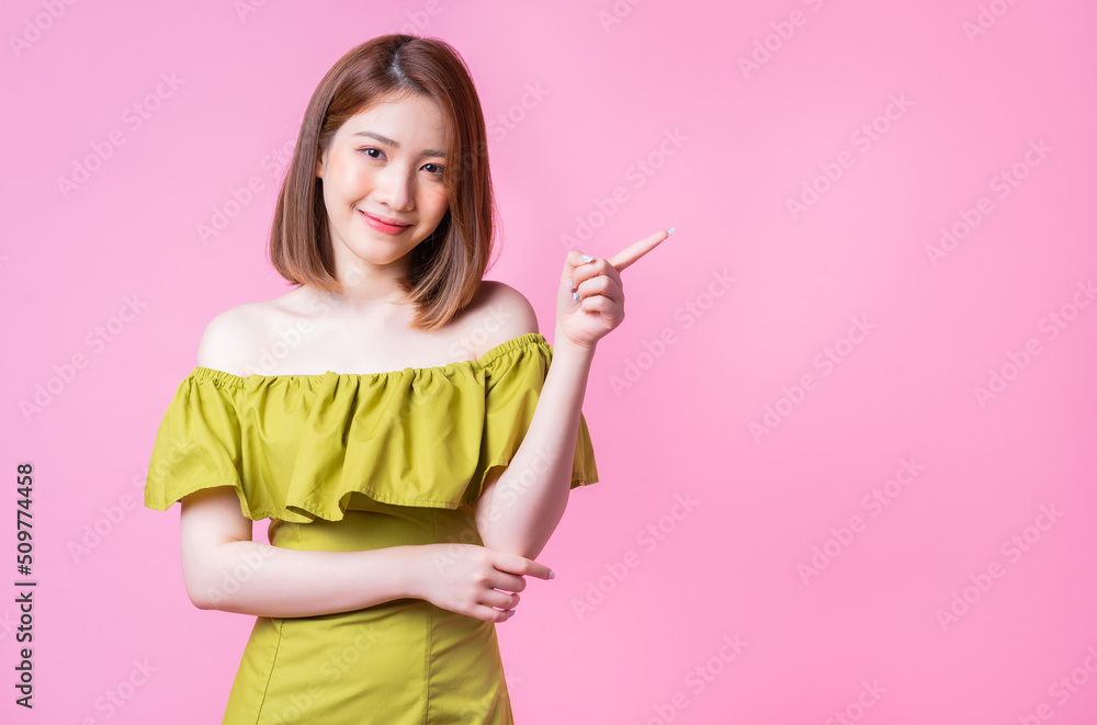 Image of young Asian woman wearing green dress on pink background Image of young Asian woman wearing green dress on pink background