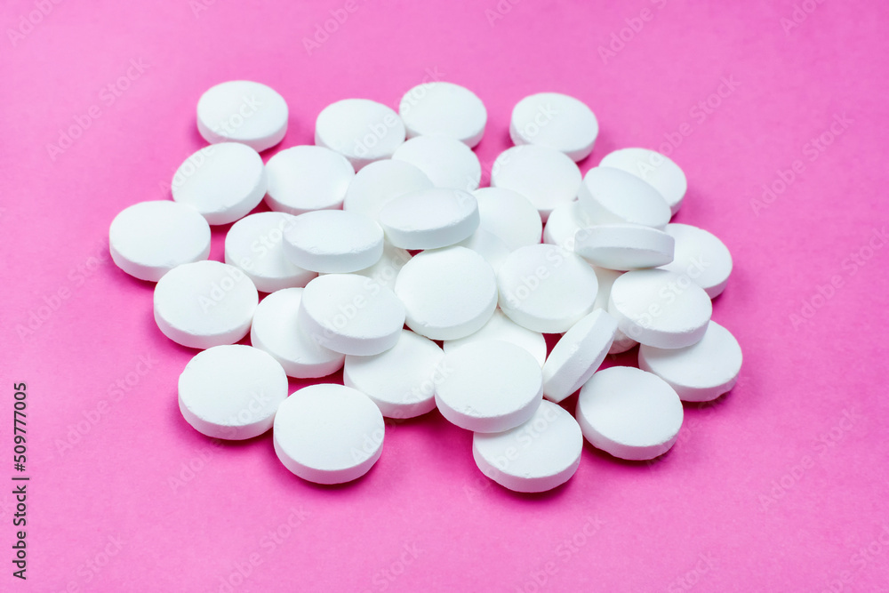 Large white calcium tablets on a bright pink background. Ca. Close-up. Large white calcium tablets on a bright pink background. Ca. Close-up.