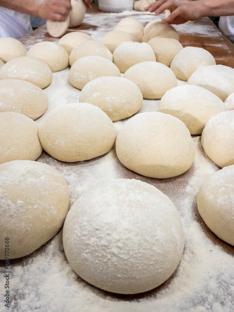 Raw of dough for pizza and bread, with hands working at the back Raw of dough for pizza and bread, with hands working at the back