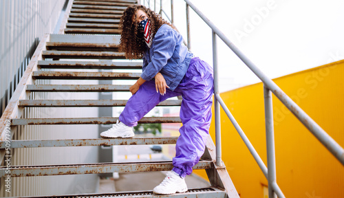 Street dancer in stylish clothes with american bandana dancing and showing some moves. Sport, dancing and urban culture concept.