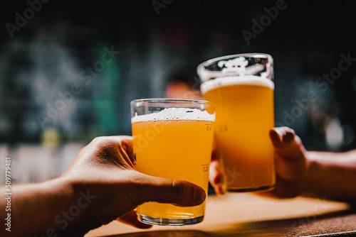 Print op canvas Two friends hands toasting with glasses of light beer at the pub or bar