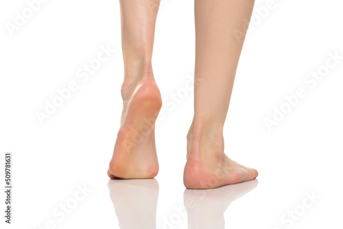 Back view of a beautifully cared female bare feet on a white background