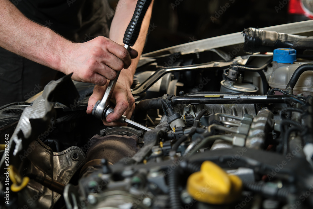 Close up of car mechanic hands doing car service and maintenance. Mechanics workshop. Close up of car mechanic hands doing car service and maintenance. Mechanics workshop.