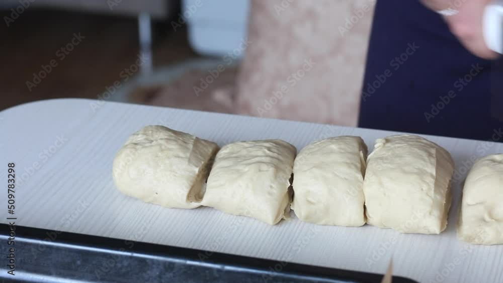 A woman cuts dough pieces with a knife. Preparing donuts in the form of a flower. Close-up.