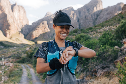 Smiling female taking a break during hike looking at smart watch