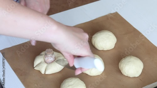 The woman forms the dough in the form of flowers. Cuts lumps of dough. Preparing donuts in the form of a flower. Close-up. photo