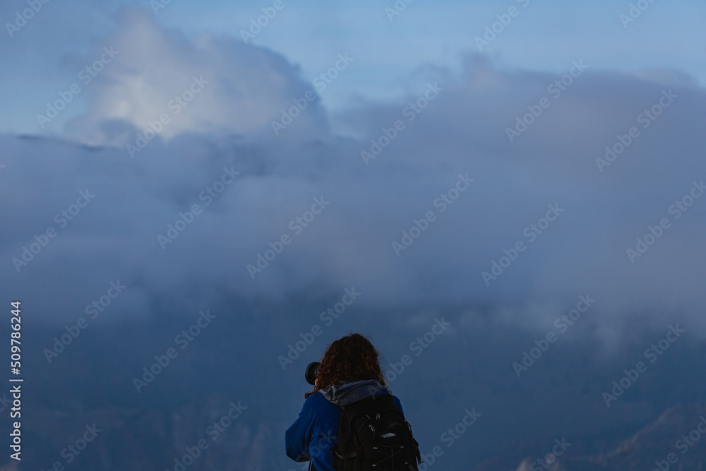 A hiker takes pictures of the landscape of the Orobie Alps seen from the Val Seriana during an October day, near the town of Clusone, Italy - October 2021.