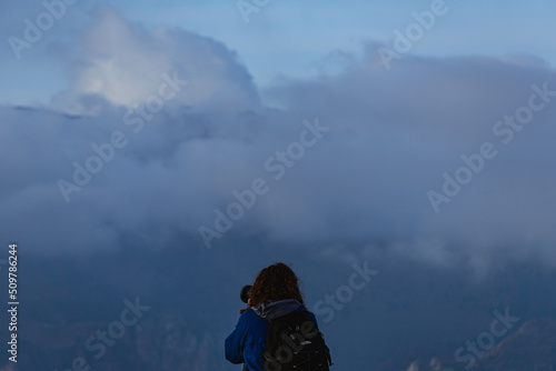 A hiker takes pictures of the landscape of the Orobie Alps seen from the Val Seriana during an October day, near the town of Clusone, Italy - October 2021.