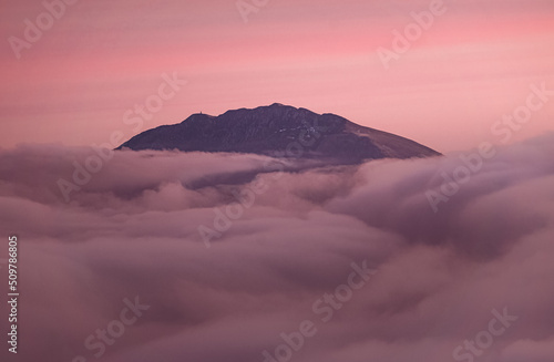 The Orobie Alps at sunset, shrouded in clouds, during an autumn evening, near the town of Castione della presolana, Italy - October 2021. photo