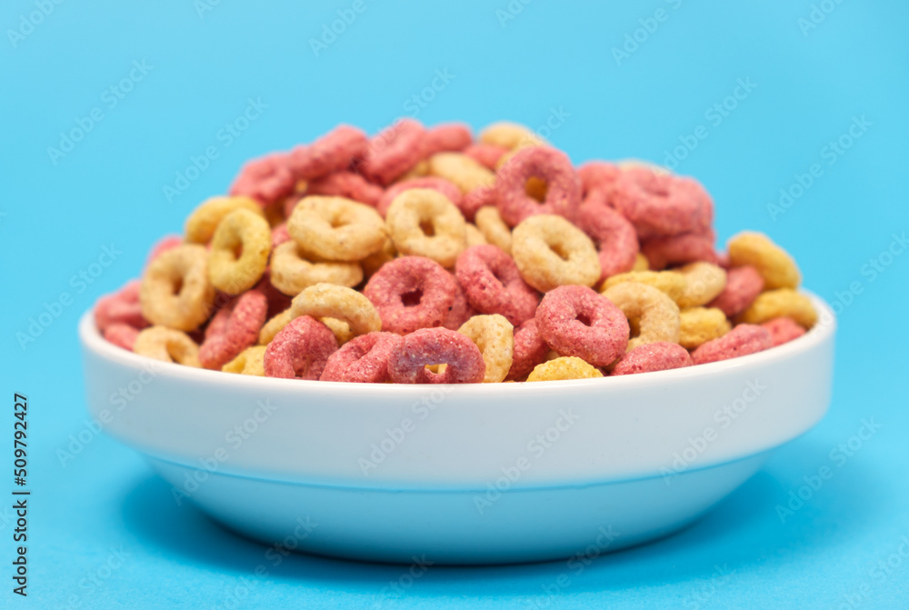 Quick cereal breakfast in the form of rings on a plate on a blue background Quick cereal breakfast in the form of rings on a plate on a blue background