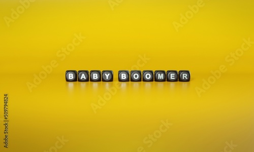 Term ‘Baby boomer’ spelled out in white text on dark wooden blocks against plain yellow background. 3D rendering photo