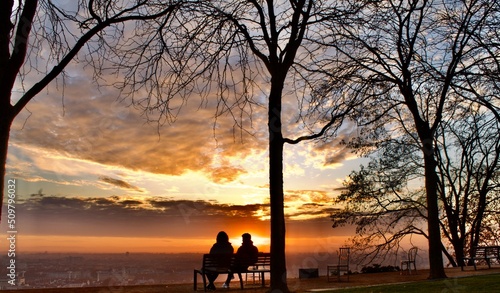 2 lovers sitting on a bench admiring a wonderful sunrise over the city of Lyon in France
