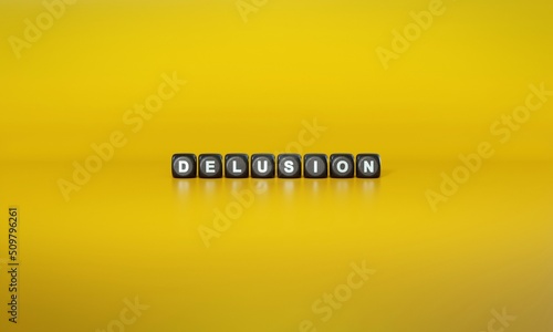 Slika na platnu Word ‘Delusion’ spelled out in white text on dark wooden blocks against plain yellow background