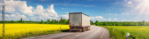Truck moving on the asphalt country highway in sunny day in spring.
