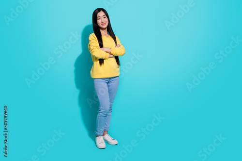 Full length photo of sweet pretty woman wear yellow pullover arms crossed empty space isolated teal color background
