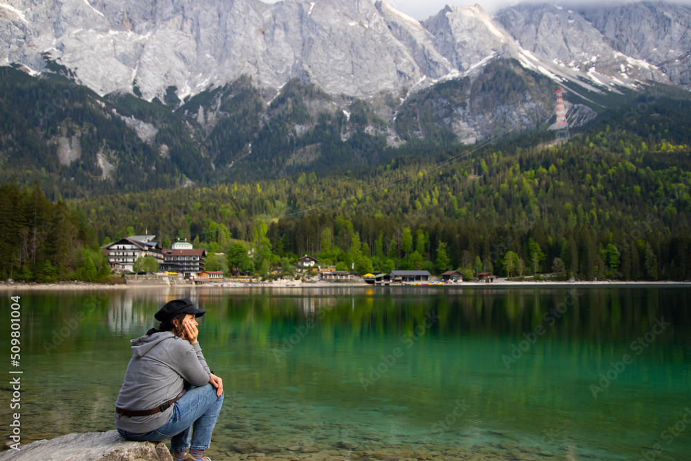 Caucasian female sitting on a stone near the Eibsee Lake, Germany. Travel, lifestyle concept. Caucasian female sitting on a stone near the Eibsee Lake, Germany. Travel, lifestyle concept.