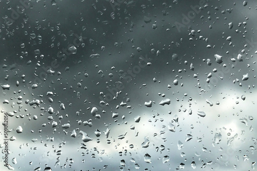 Abstract backgrounds with raindrops on window and blurred day cloudy sky