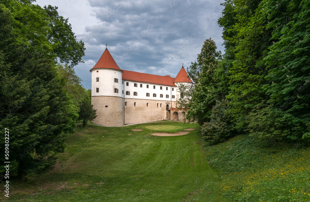 Castle Mokrice on a spring evening with dramatic clouds and forest. A fortress in the woods. 

