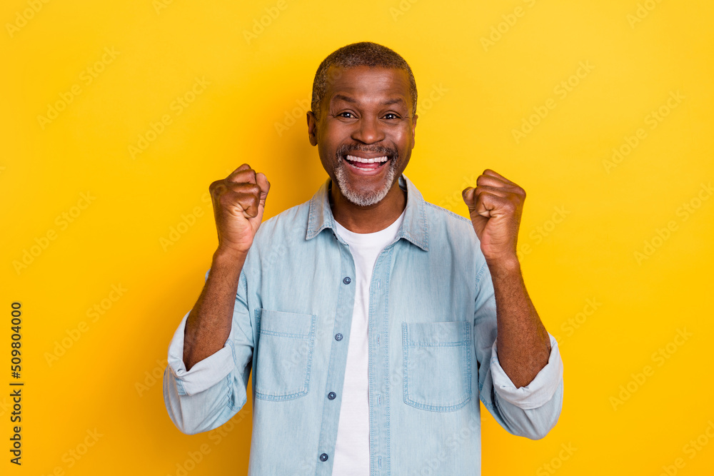 Photo of astonished successful person raise fists shout yes isolated on yellow color background Photo of astonished successful person raise fists shout yes isolated on yellow color background