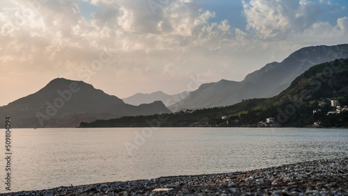 Sunset with mountain view in Bar Montenegro. Embankment of Bar.  View of the green mountains and the sea in Montenegro. Resort town. Resting on the beach by the sea. Bathing season. Holiday season