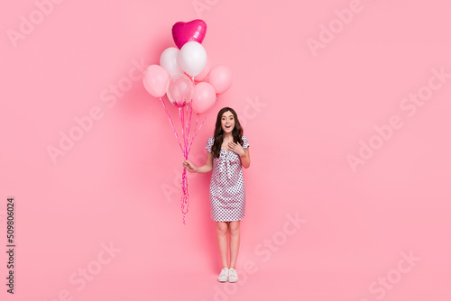 Photo of adorable impressed woman wear white dress arm chest holding air balls isolated pink color background