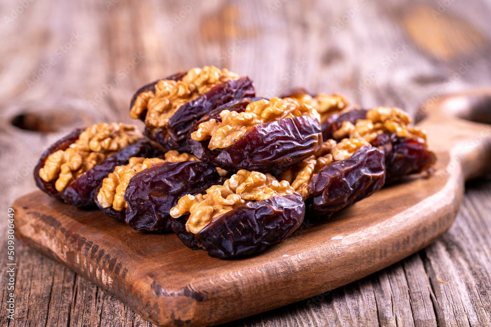 Fototapeta premium Walnut-stuffed dates on a wood floor. Close-up. Arabian luxury for special occasions such as Ramadan and Eid holidays. local name cevizli hurma