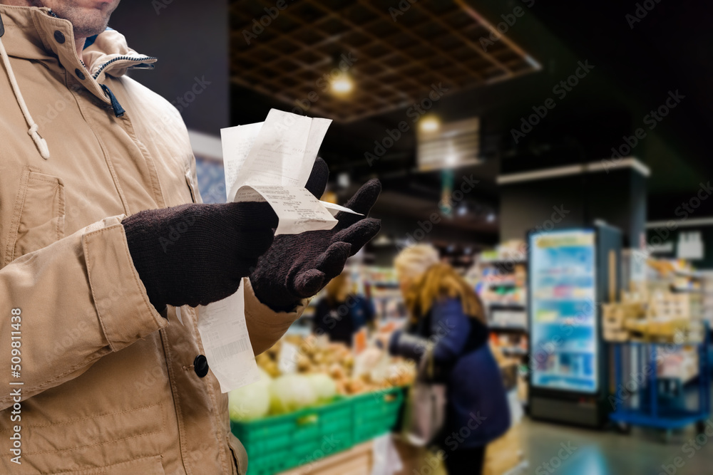 Male customer holding long shopping bill while buying food in the supermarket