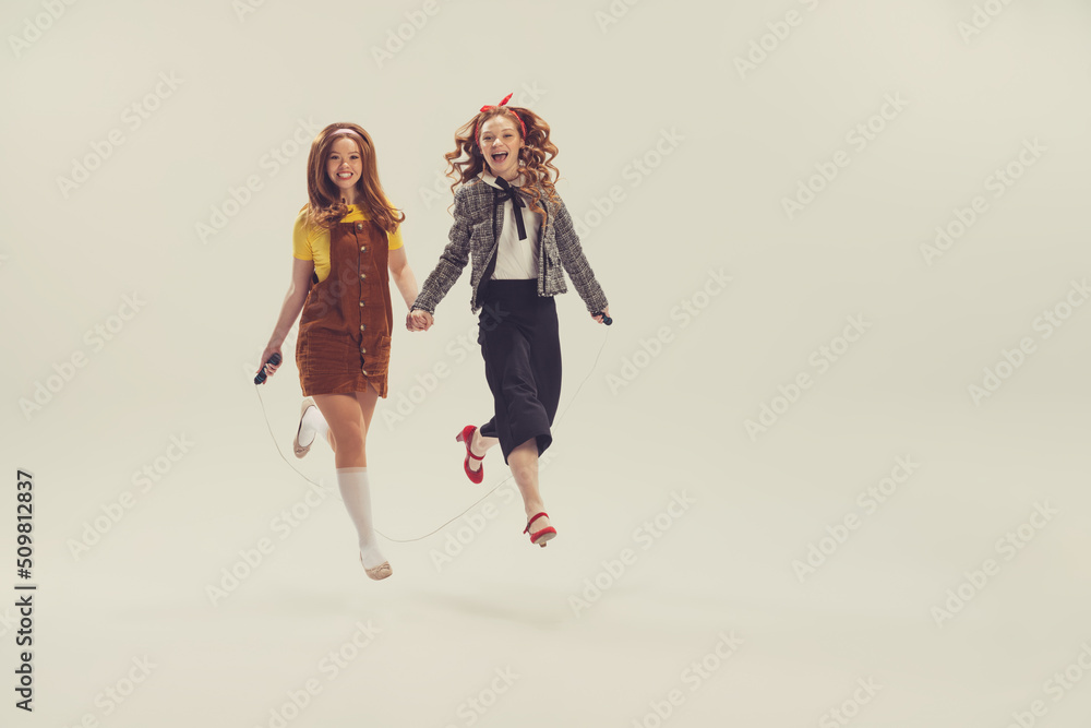 Pretty young girls in retro 80s, 90s fashion style, outfits isolated over white studio background. Concept of eras comparison, beauty, fashion and youth. Pretty young girls in retro 80s, 90s fashion style, outfits isolated over white studio background. Concept of eras comparison, beauty, fashion and youth.