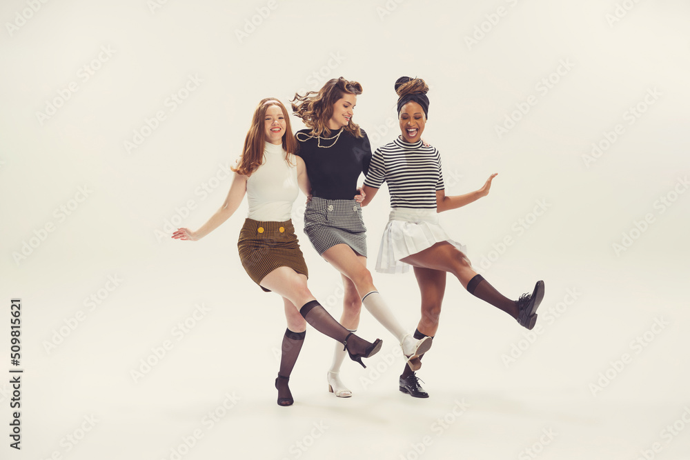 Pretty young girls in retro 80s, 90s fashion style, outfits isolated over  white studio background. Concept of eras comparison, beauty, fashion and  youth. Stock Photo
