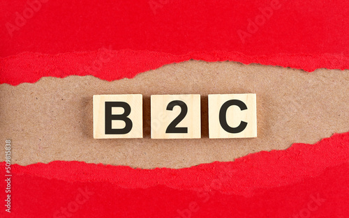 B2C word on wooden cubes on red torn paper , financial concept background