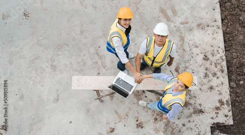 Top view of three construction engineers and workers meeting, planning for successfully building houses. Overhead view at group of Asian labor people working together at residential construction site