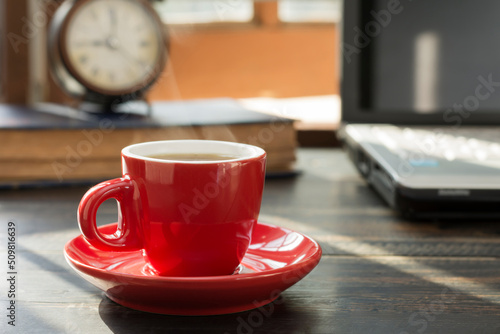 A red coffee cup is placed on the desk. office or at home with a notebook computer keyboard tablet pc
